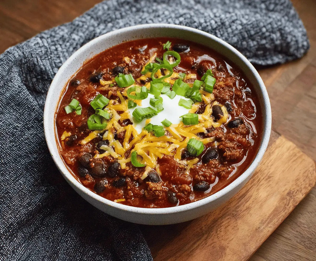 Spicy black bean chili topped with fresh cilantro and diced onions in a rustic bowl, perfect for a hearty vegetarian meal.