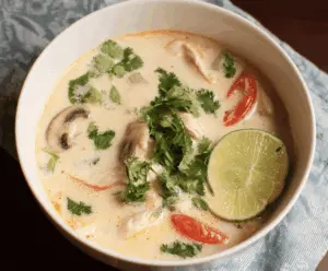 Delicious bowl of Thai Coconut Chicken Soup (Tom Kha Gai) with tender chicken, fresh herbs, and creamy coconut milk in a vibrant, flavorful broth