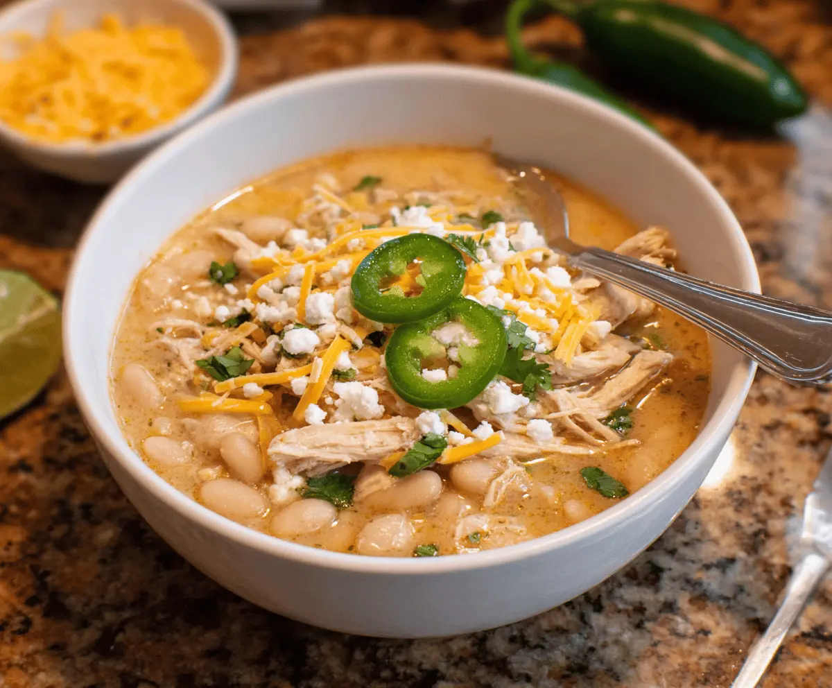 Creamy white chicken chili with shredded chicken, white beans, and green chilies in a savory broth, garnished with fresh cilantro and diced onions.