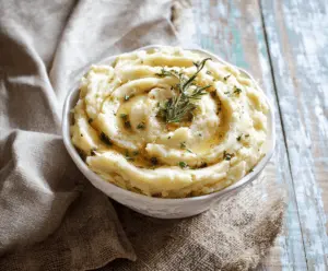 Creamy brown butter garlic mashed potatoes served in a rustic bowl, garnished with fresh herbs.