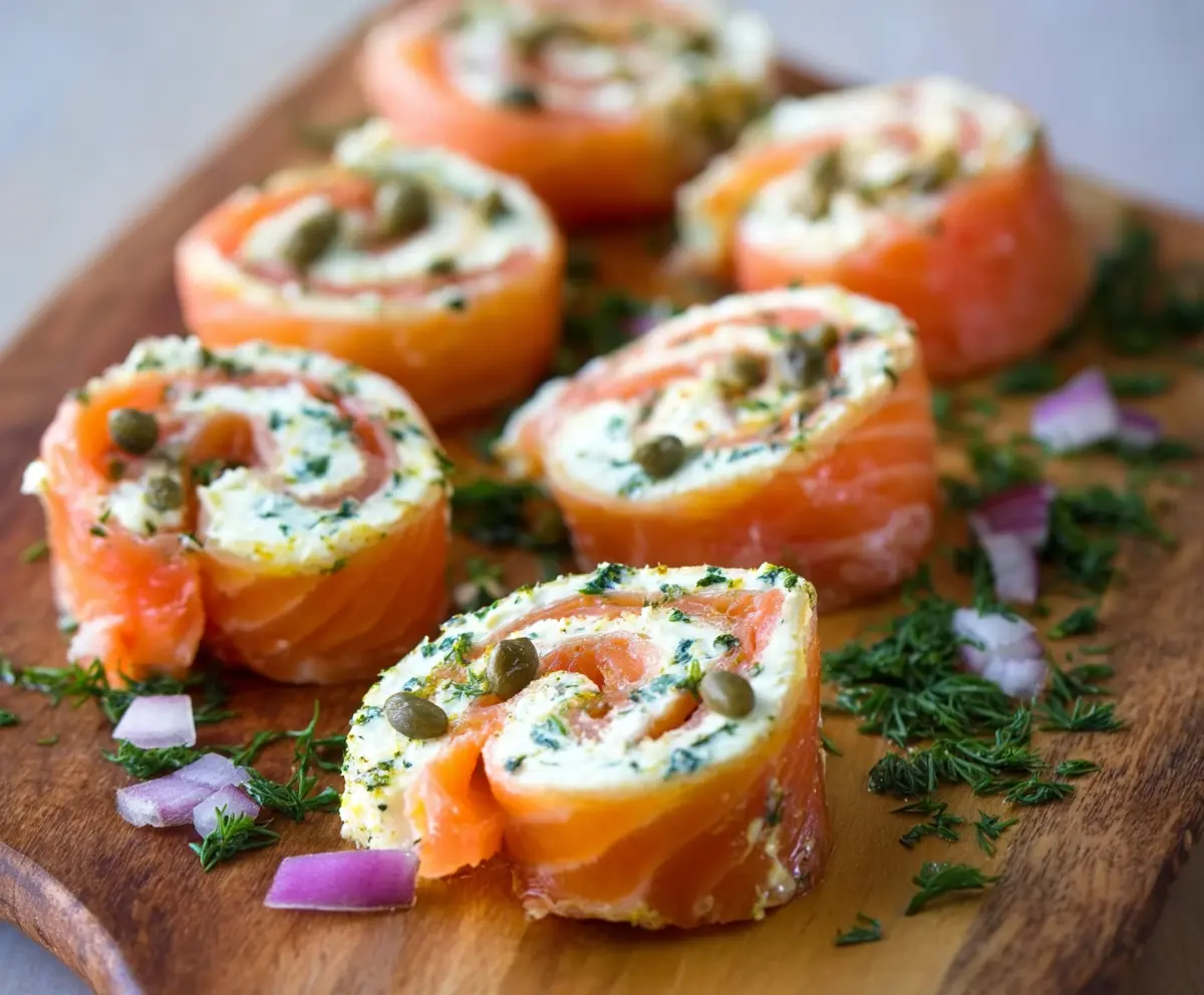 Delicious smoked salmon pinwheels garnished with fresh herbs on a white platter