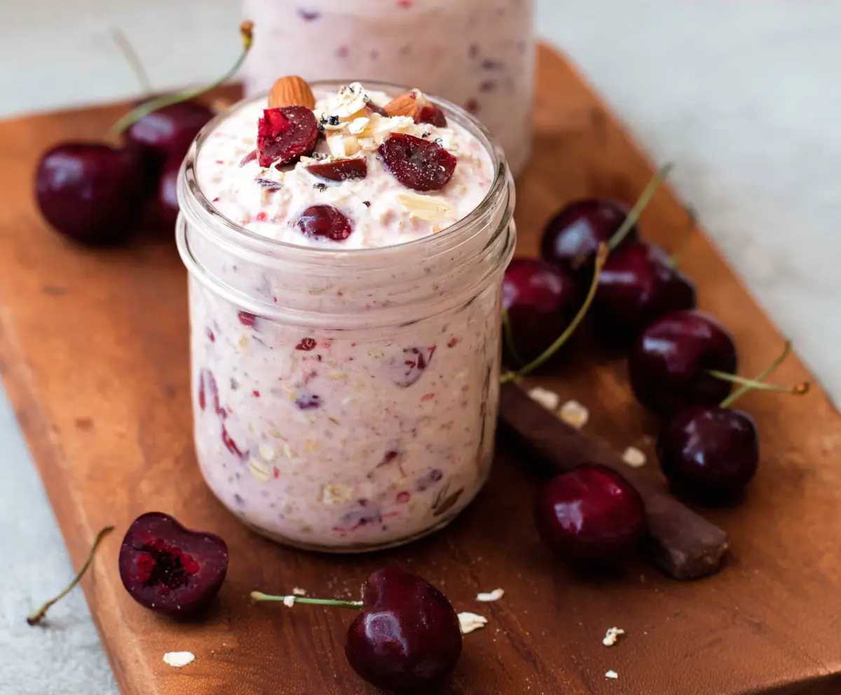 Delicious Cherry Overnight Oats in a glass jar topped with fresh cherries and creamy yogurt.