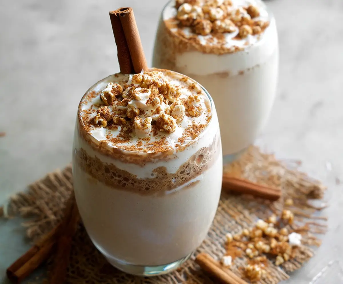 Creamy Cinnamon Roll Protein Shake in a glass topped with cinnamon and whipped cream
