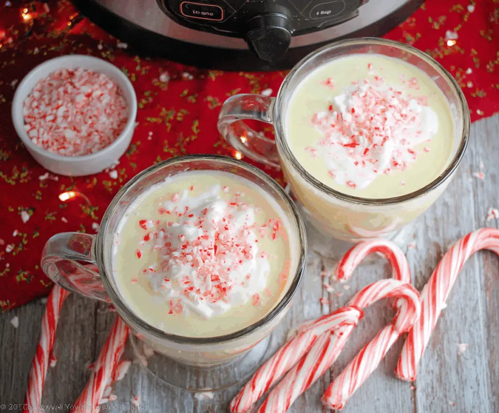 Creamy crockpot candy cane white hot chocolate served in a festive mug with whipped cream and peppermint topping.
