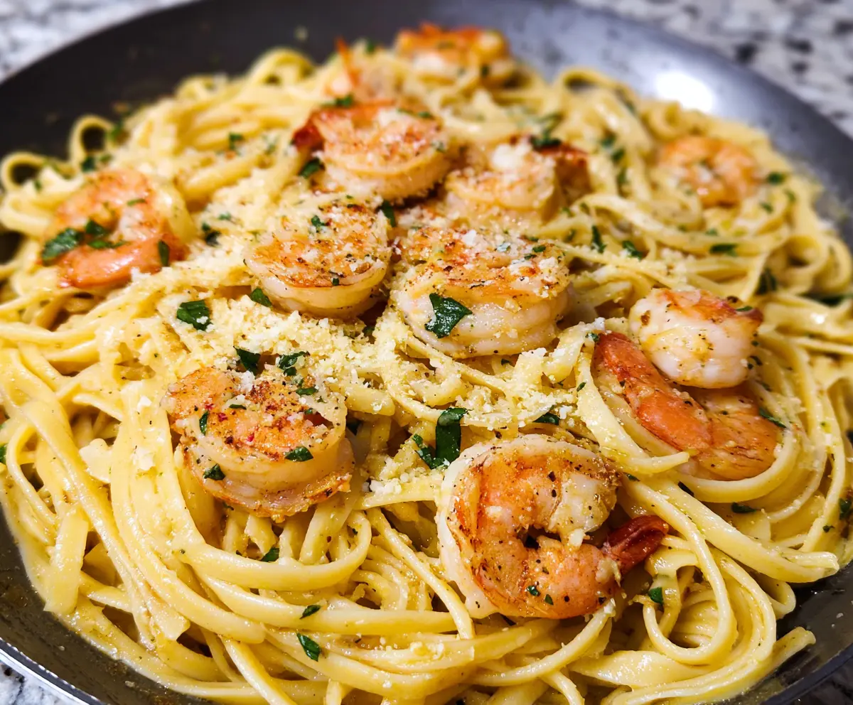 Delicious linguine shrimp scampi served with fresh herbs and lemon slices on a white plate.