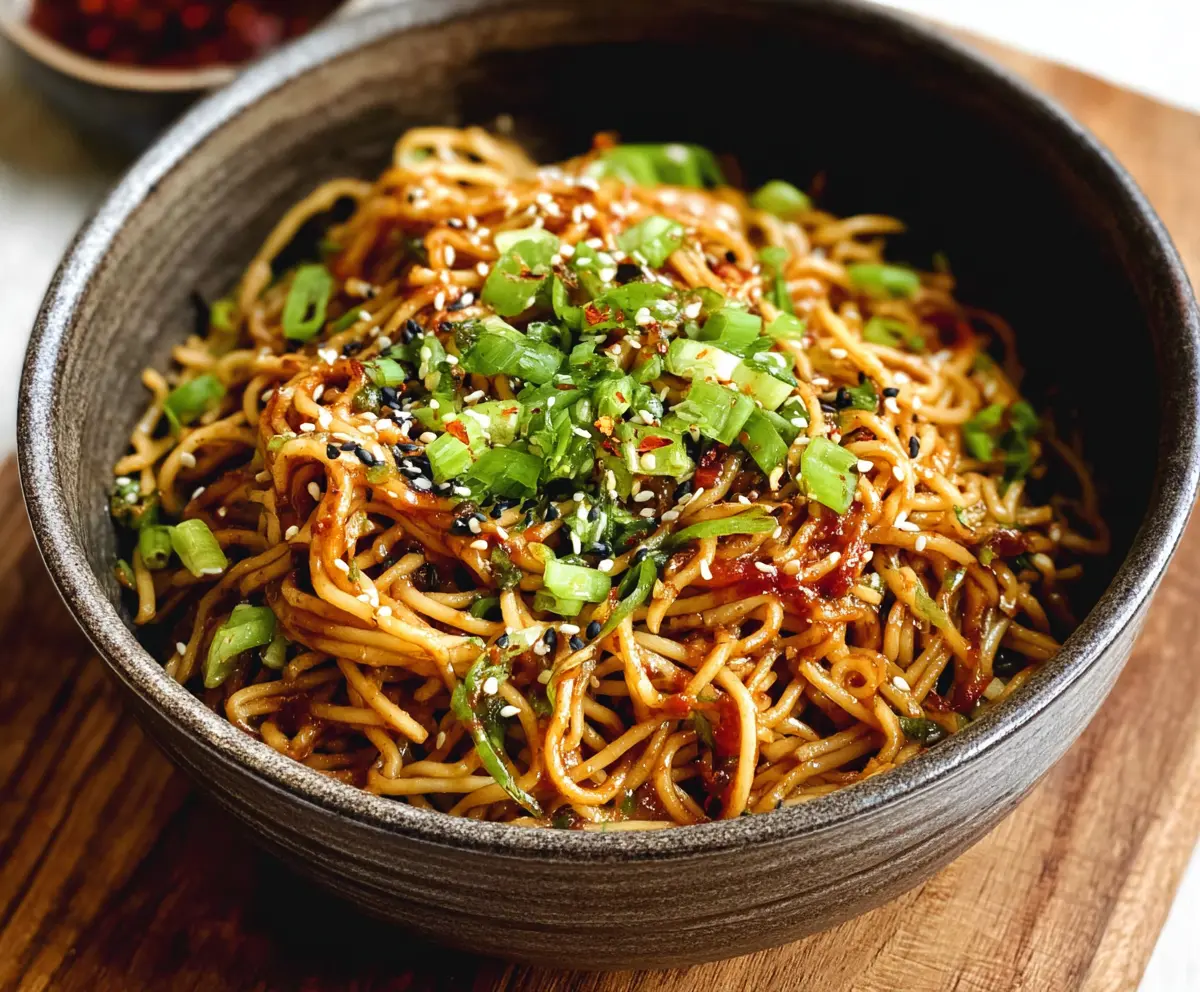 Close-up of savory Sesame Garlic Noodles garnished with sesame seeds and chopped green onions.