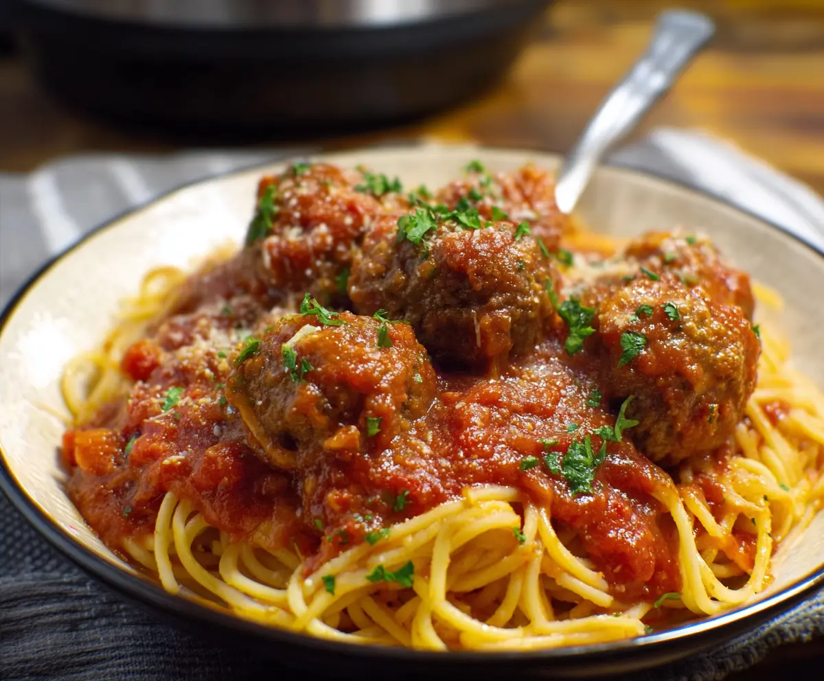 Delicious crockpot spaghetti and meatballs served in a bowl, garnished with fresh herbs.