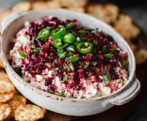 Creamy cranberry jalapeno dip with a splash of vibrant red and green colors, served with crackers.