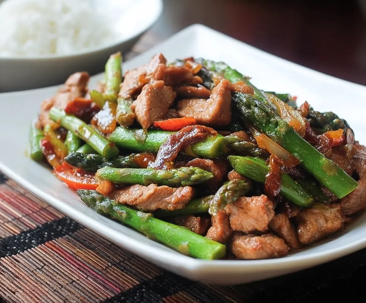 Delicious pork and asparagus stir fry served in a bowl, highlighting fresh vegetables and juicy pork pieces.