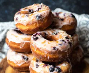 Delicious blueberry cake donuts garnished with fresh blueberries on a white plate.
