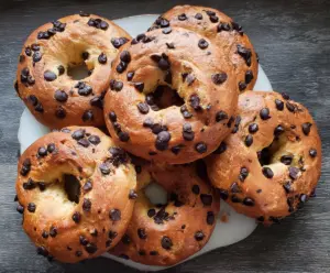 Delicious homemade chocolate chip bagels on a wooden cutting board with chocolate chunks.