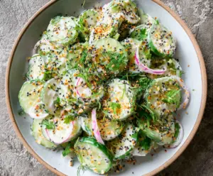 Fresh cucumber slices on a vibrant bagel salad topped with sesame seeds and everything seasoning.