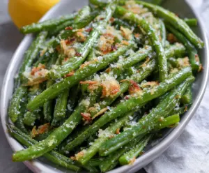Delicious Garlic Parmesan Green Beans plated on a white dish with fresh garlic and Parmesan cheese.