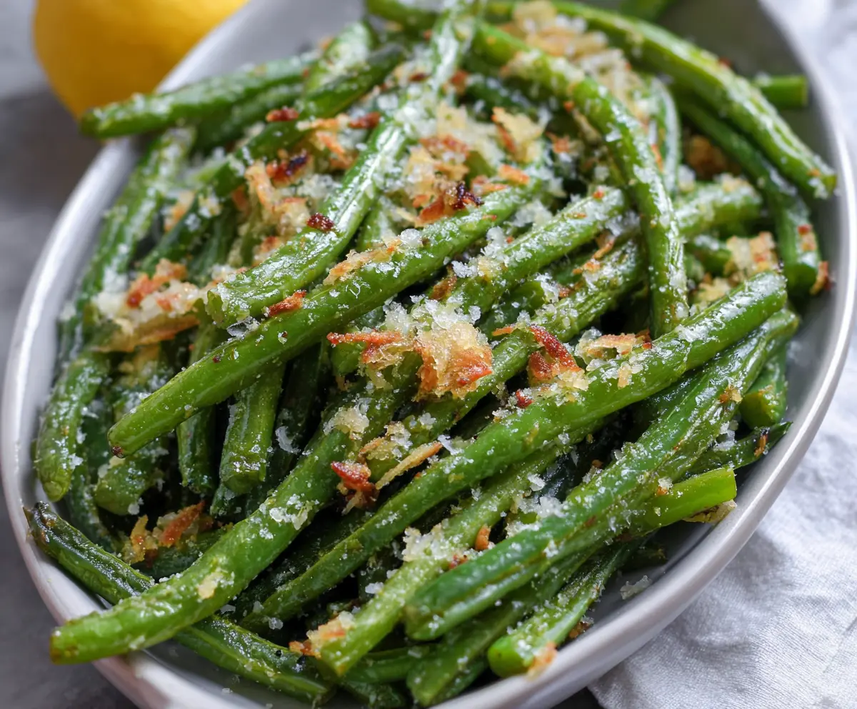 Delicious Garlic Parmesan Green Beans plated on a white dish with fresh garlic and Parmesan cheese.