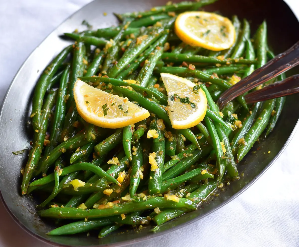 Fresh Lemon Green Beans dish garnished with lemon slices and herbs on a white plate.