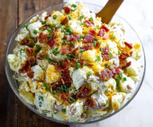 Creamy loaded potato salad with bacon, cheese, and scallions served in a bowl