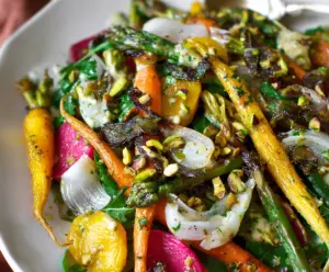 Colorful spring root vegetable salad topped with pistachio vinaigrette, perfect for a fresh, healthy meal.